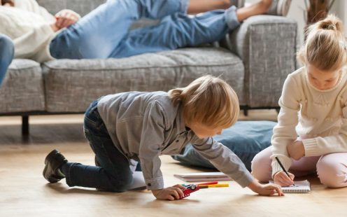 Horizontal image little kids play drawing on warm floor parents resting on couch family spend free time together, leisure activity at modern comfortable home concept, banner for website header design